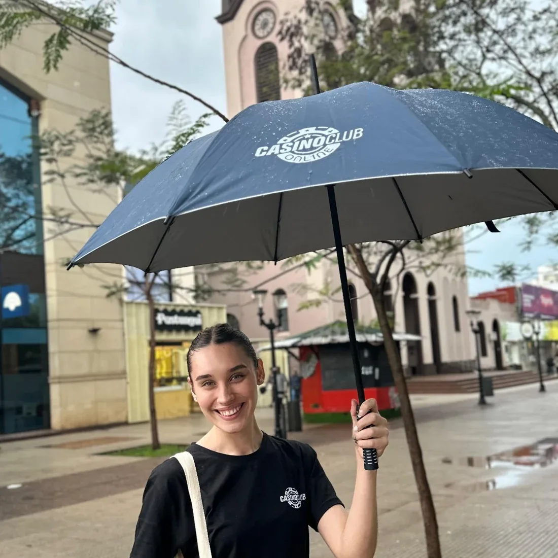 SOMOS brand ambassador with a branded umbrella at a street marketing activation in Posadas, Misiones